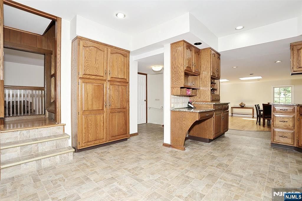 The interior threshold between the kitchen and a larger open family/dining area, with oak millwork, tile flooring and a step-down living space visible in the distance