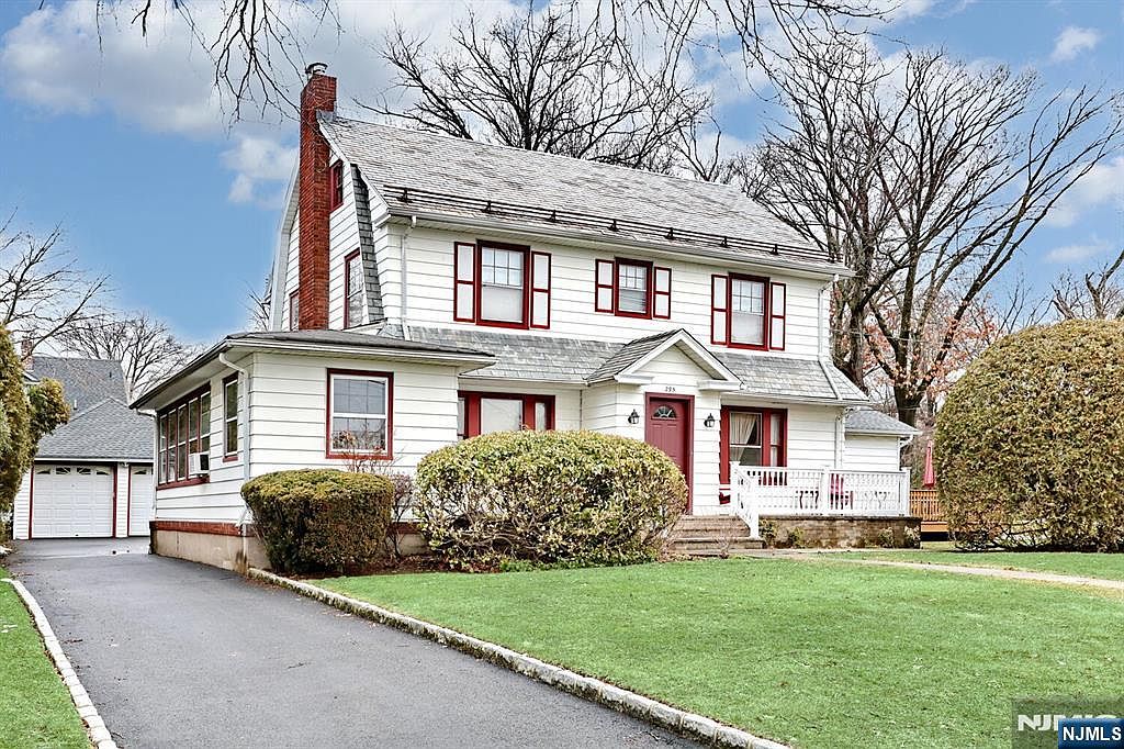 A wider winter view of the property showing the depth of the front yard, the driveway sweeping back to the garage, and the scale of the 18,000 square foot lot relative to the house